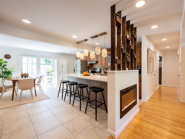 94 Shadyside Ave, Port Washington, NY 11050 - kitchen featuring appliances with stainless steel finishes, a kitchen breakfast bar, decorative backsplash, recessed lighting, and hanging light fixtures