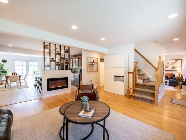 94 Shadyside Ave, Port Washington, NY 11050 - living area featuring a glass covered fireplace, light wood-style floors, stairway, and recessed lighting