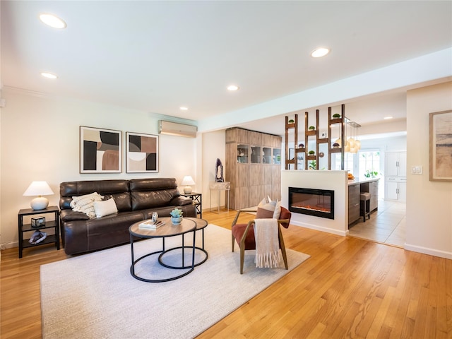 94 Shadyside Ave, Port Washington, NY 11050 - living area featuring a wall unit AC, a glass covered fireplace, recessed lighting, light wood-style floors, and baseboards