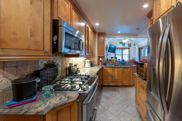 kitchen featuring appliances with stainless steel finishes, brown cabinets, a sink, and recessed lighting
