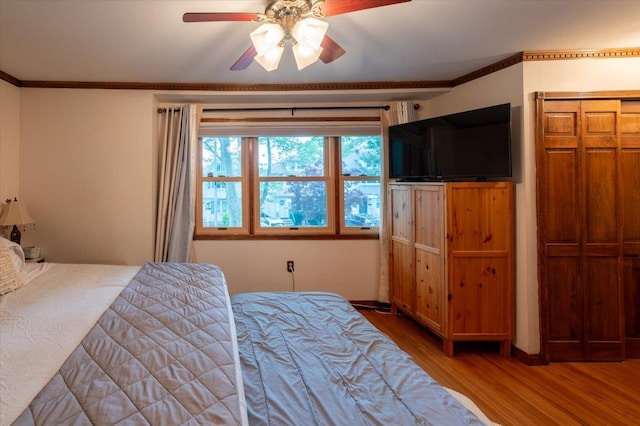 bedroom featuring wood finished floors, crown molding, and ceiling fan