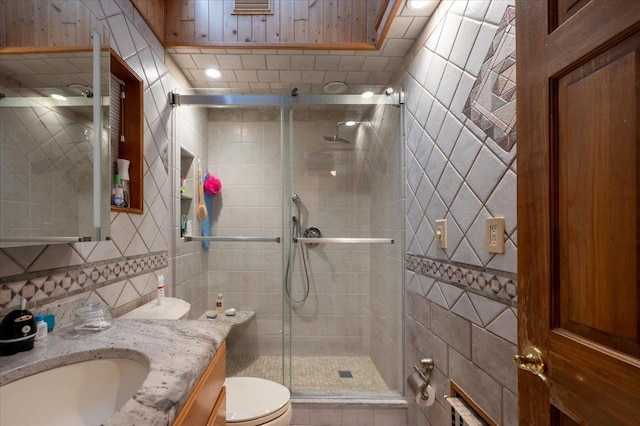 full bathroom with tile walls, toilet, a shower stall, and vanity