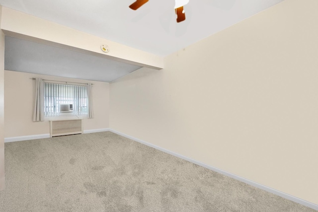 carpeted spare room with vaulted ceiling, baseboards, and a ceiling fan