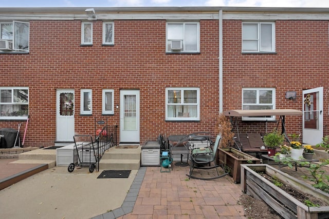 back of house featuring brick siding, a patio, and cooling unit