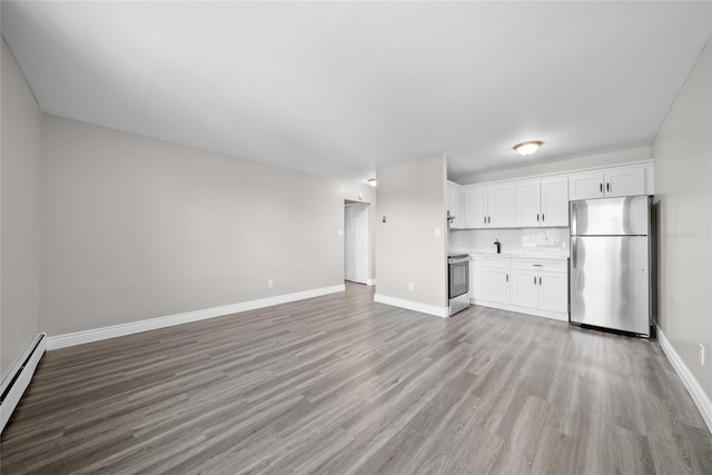 280 Lowndes Ave Unit 305G, Huntington Station, NY 11746 - unfurnished living room with light wood-style flooring, a baseboard heating unit, baseboards, and a sink