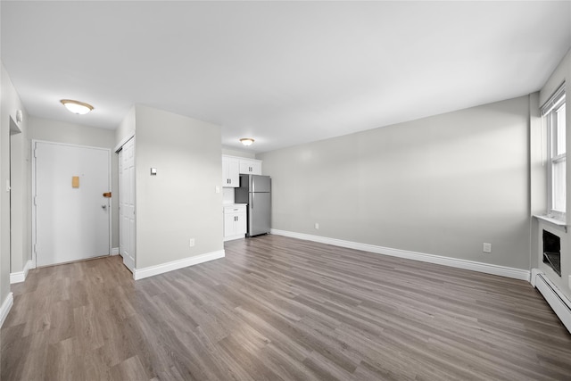 280 Lowndes Ave Unit 305G, Huntington Station, NY 11746 - unfurnished living room with wood finished floors, baseboards, and baseboard heating