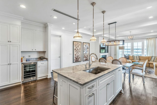 kitchen featuring a sink, beverage cooler, dark wood-style floors, a kitchen breakfast bar, and ornamental molding