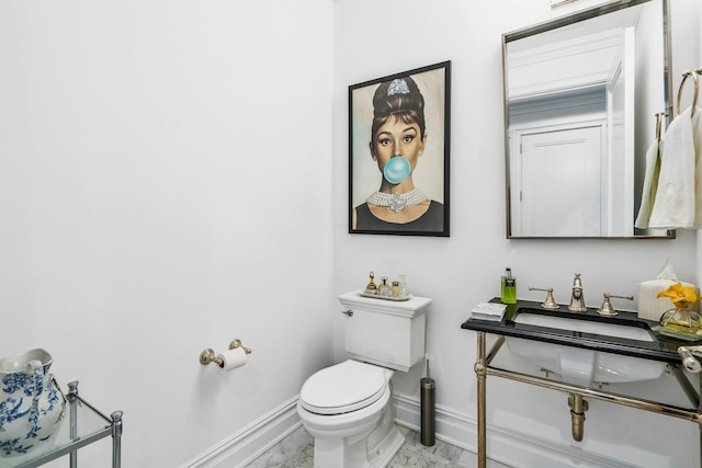 bathroom with baseboards, toilet, and a sink