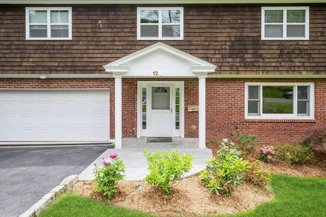 12 Glenn Pl, Hastings-On-Hudson, NY 10706 - view of front facade with asphalt driveway, an attached garage, and brick siding