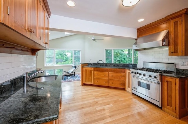 12 Glenn Pl, Hastings-On-Hudson, NY 10706 - kitchen with wall chimney exhaust hood, premium range, a sink, brown cabinetry, and lofted ceiling