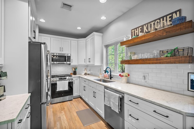 40 Peter Turner Rd, Monroe, NY 10950 - kitchen with stainless steel appliances, a sink, open shelves, backsplash, and white cabinets