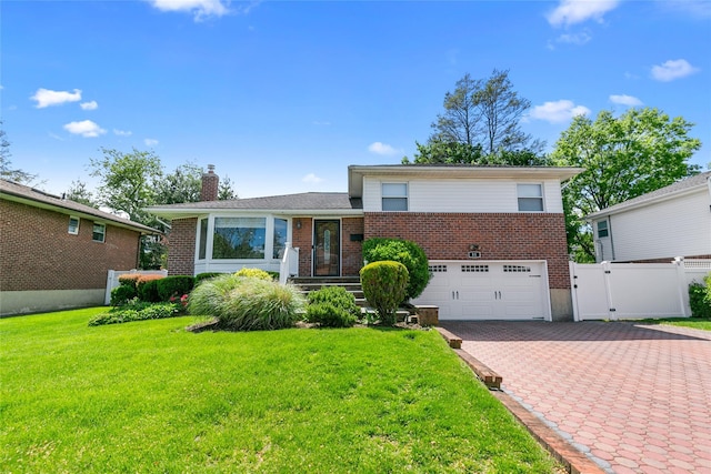 tri-level home featuring brick siding, a garage, decorative driveway, a chimney, and a gate
