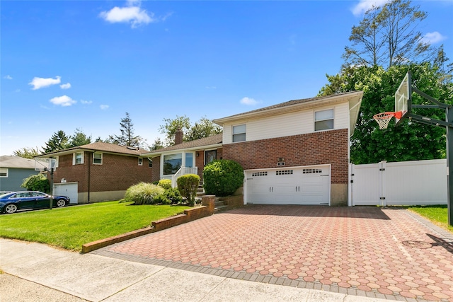 tri-level home featuring brick siding, driveway, a gate, a garage, and a chimney