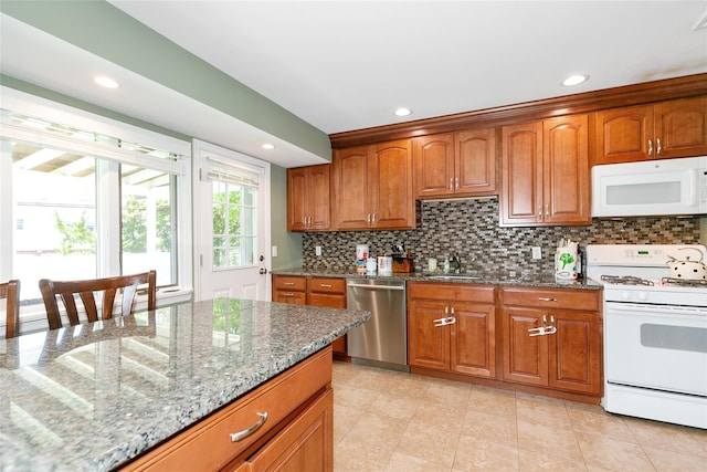 kitchen with white appliances, a sink, stone countertops, brown cabinetry, and backsplash
