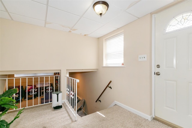 carpeted foyer entrance with a paneled ceiling and baseboards
