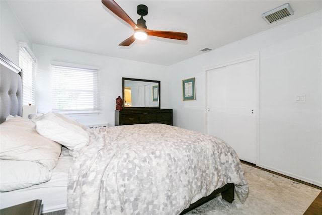 bedroom with wood finished floors, ceiling fan, a closet, and baseboards