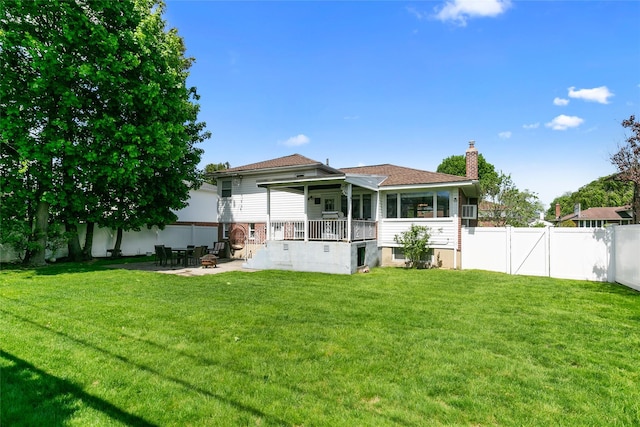 rear view of property featuring a chimney, a patio area, and a sunroom