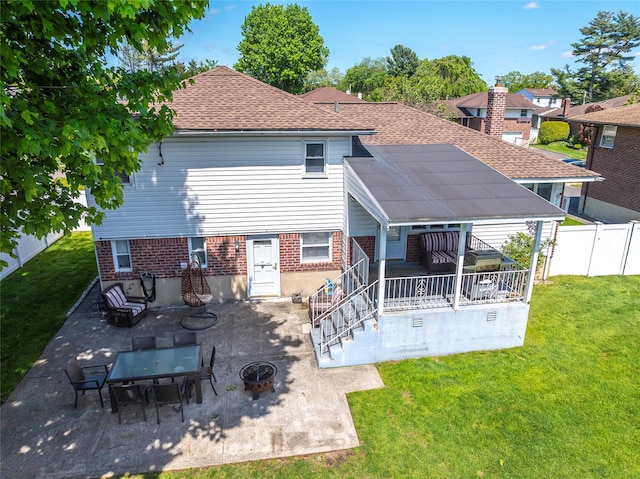 rear view of property featuring a patio, an outdoor fire pit, brick siding, and roof with shingles