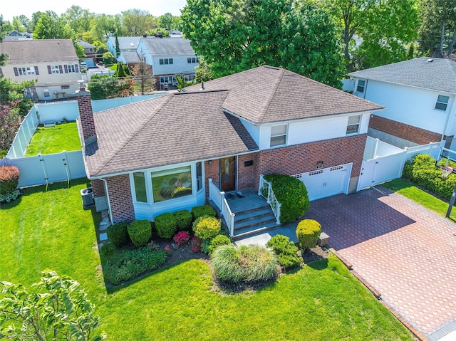 view of front facade featuring brick siding, a gate, a shingled roof, and decorative driveway