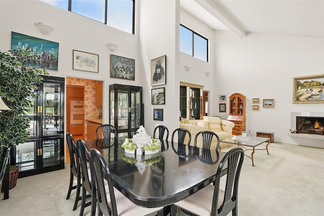 16 Waters Edge Unit 16, Rye, NY 10580 - dining space featuring light colored carpet, a towering ceiling, and a lit fireplace