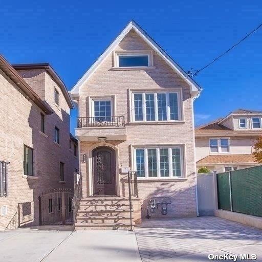 view of front of property featuring brick siding, a balcony, and fence