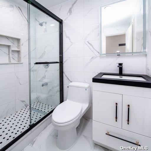 full bathroom featuring a shower stall, marble finish floors, toilet, and vanity