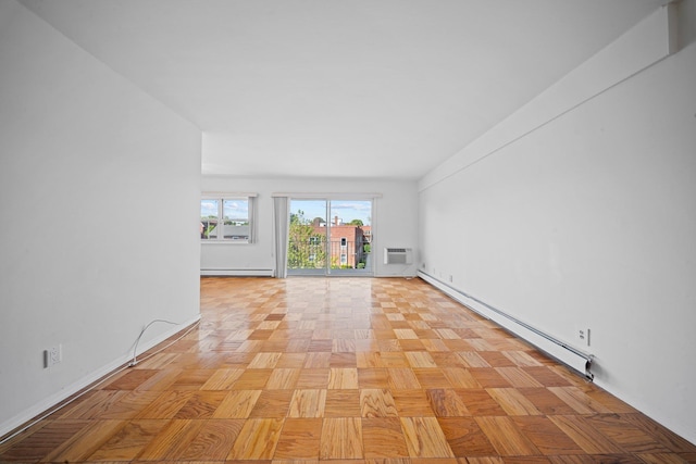 empty room featuring a baseboard radiator, baseboards, and a wall unit AC