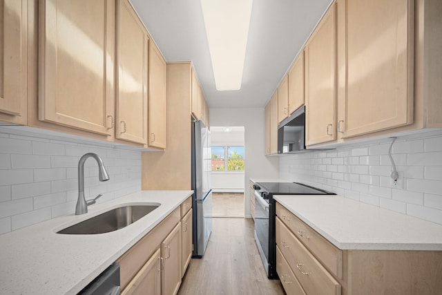 kitchen featuring electric range, a sink, light brown cabinetry, freestanding refrigerator, and light wood finished floors