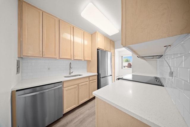 kitchen with appliances with stainless steel finishes, a sink, and light brown cabinetry