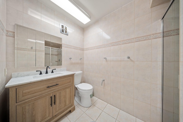 bathroom with tile walls, a stall shower, toilet, tile patterned floors, and vanity