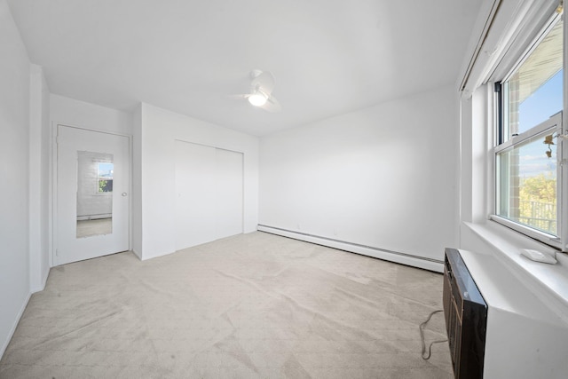 unfurnished bedroom featuring a baseboard heating unit, light carpet, ceiling fan, and a closet