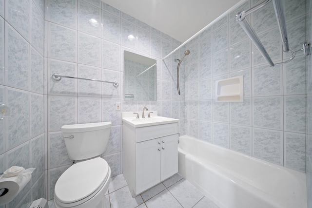 full bath with tile walls, tile patterned floors, shower / bathtub combination, toilet, and vanity
