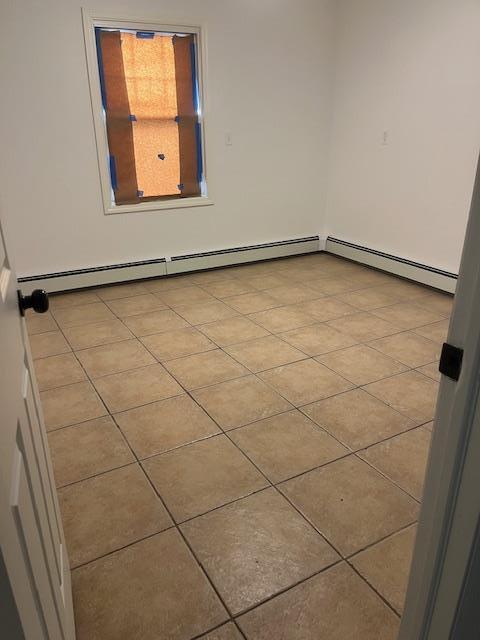 664 Bryant St, Westbury, NY 11590 - tiled empty room with baseboard heating