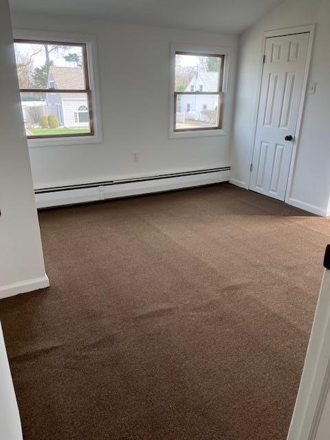 664 Bryant St, Westbury, NY 11590 - unfurnished bedroom featuring dark carpet, baseboard heating, and baseboards