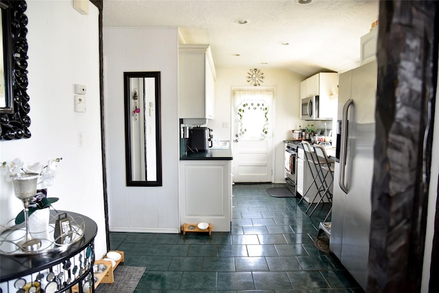 125 Timberline Dr, Brentwood, NY 11717 - kitchen with stainless steel appliances, dark countertops, white cabinetry, dark tile patterned floors, and baseboards