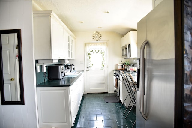 125 Timberline Dr, Brentwood, NY 11717 - kitchen with appliances with stainless steel finishes, dark countertops, white cabinets, glass insert cabinets, and lofted ceiling