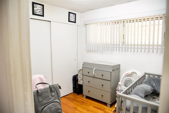125 Timberline Dr, Brentwood, NY 11717 - bedroom featuring a closet, wood finished floors, multiple windows, and a crib