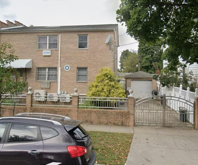214-27 38th Ave, Bayside, NY 11361 - view of front of house featuring a fenced front yard, driveway, a gate, brick siding, and an outdoor structure