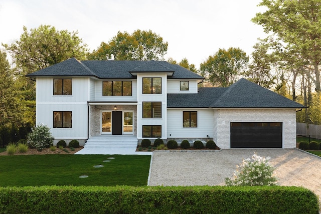 view of front of home featuring gravel driveway, an attached garage, a shingled roof, and a front lawn