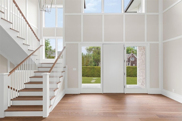 foyer featuring a towering ceiling, stairway, and wood finished floors