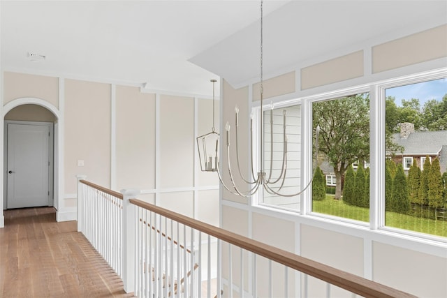 hallway featuring a chandelier, light wood-type flooring, and arched walkways