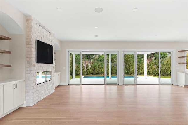 unfurnished living room with healthy amount of natural light, light wood finished floors, a large fireplace, and recessed lighting