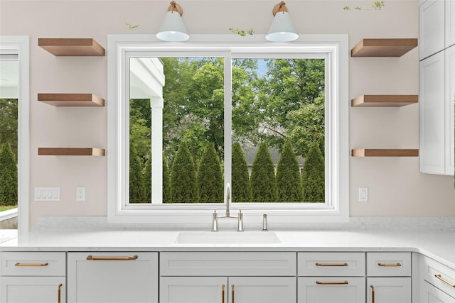 kitchen featuring open shelves, a sink, light countertops, and white cabinets
