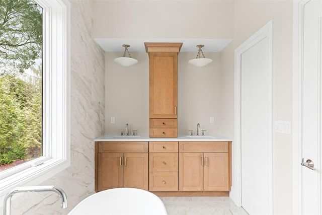 bathroom with marble finish flooring, a soaking tub, and double vanity