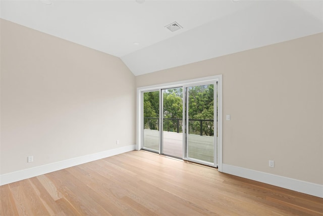 spare room with baseboards, light wood finished floors, and vaulted ceiling