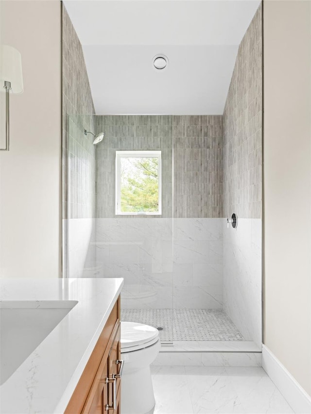full bath featuring marble finish flooring, tiled shower, toilet, vanity, and baseboards