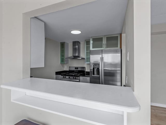 88-20 Parsons Blvd Unit 6D, Jamaica, NY 11432 - kitchen with wall chimney exhaust hood, appliances with stainless steel finishes, a peninsula, glass insert cabinets, and wood finished floors