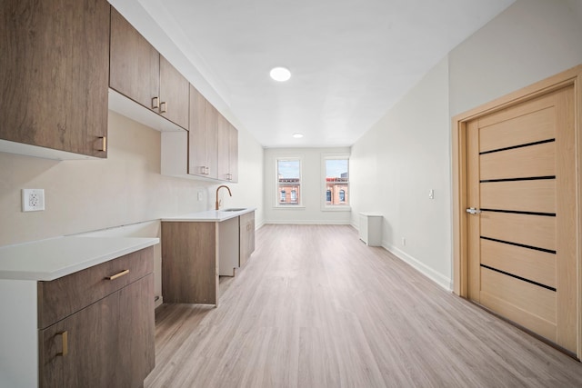 530 Sutter Ave, Brooklyn, NY 11207 - kitchen with light wood finished floors, light countertops, a sink, baseboards, and modern cabinets