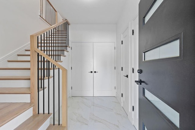 foyer featuring stairs and marble finish floors