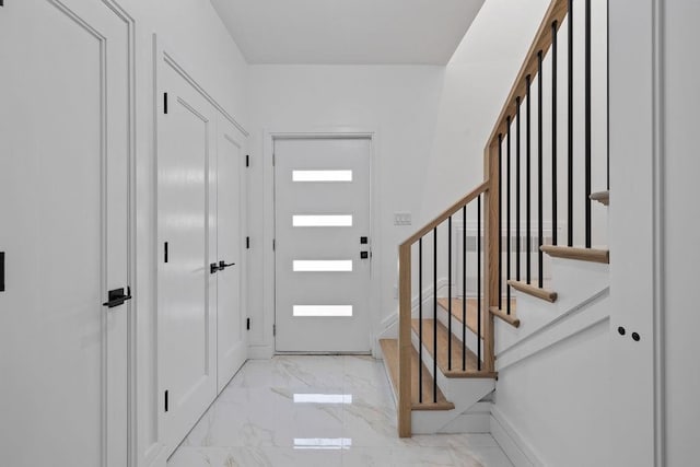 entrance foyer featuring marble finish floors, stairs, and baseboards
